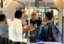A male (BLACK T-SHIRT)) slapped another rail passenger (NAVY JACKET)  before being made to apologise by fellow commuters