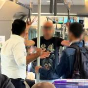 A male (BLACK T-SHIRT)) slapped another rail passenger (NAVY JACKET)  before being made to apologise by fellow commuters